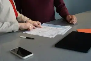 Zwei Personen gehen an einem Tisch gemeinsam Unterlagen durch