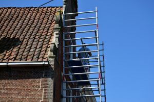 Handwerker auf einem Gerüst an der Fassade eines Backsteinhauses